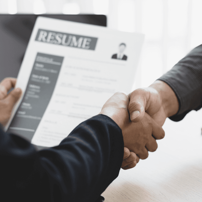 people shaking hands while one holds a resume