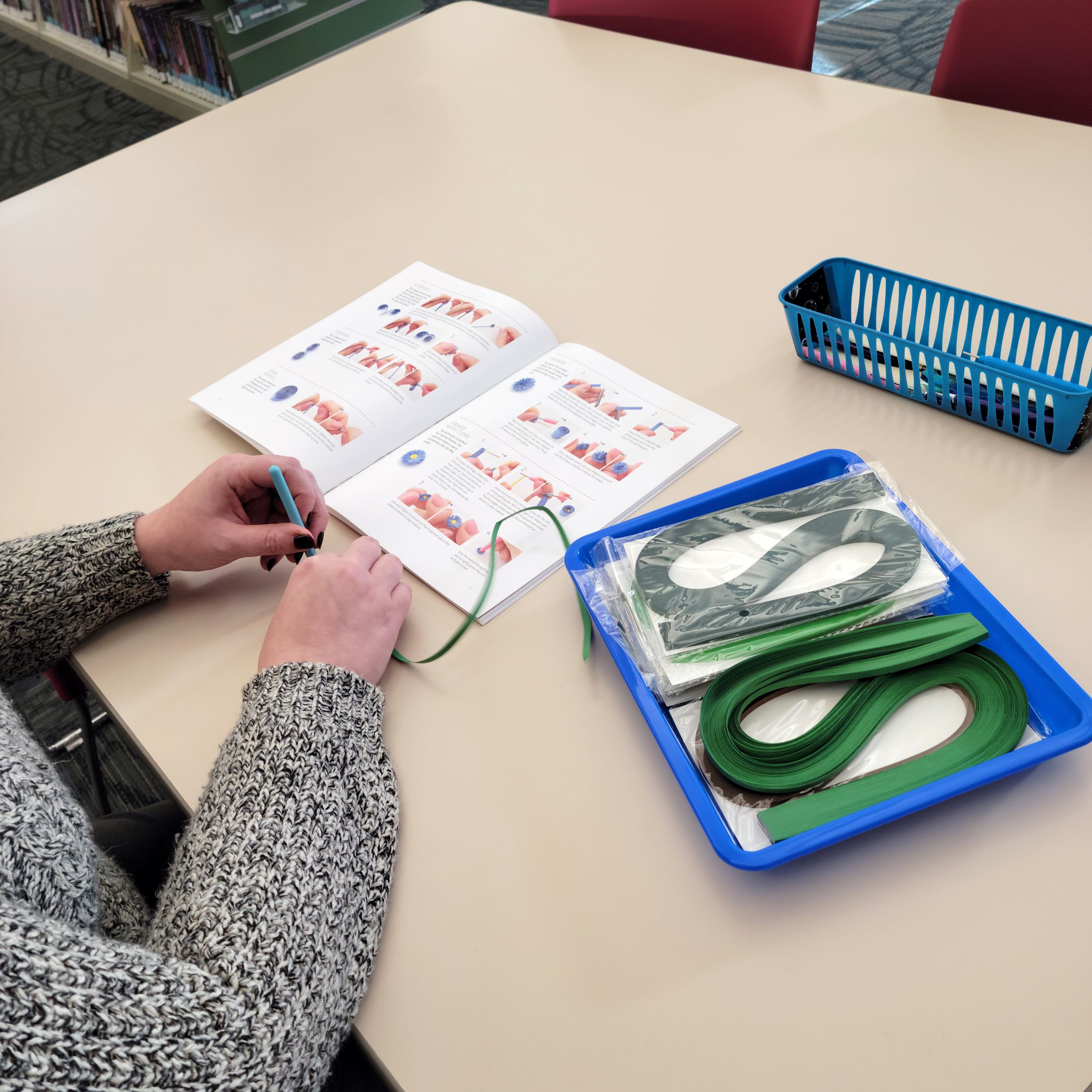 An adult using paper quilling tools to create a design