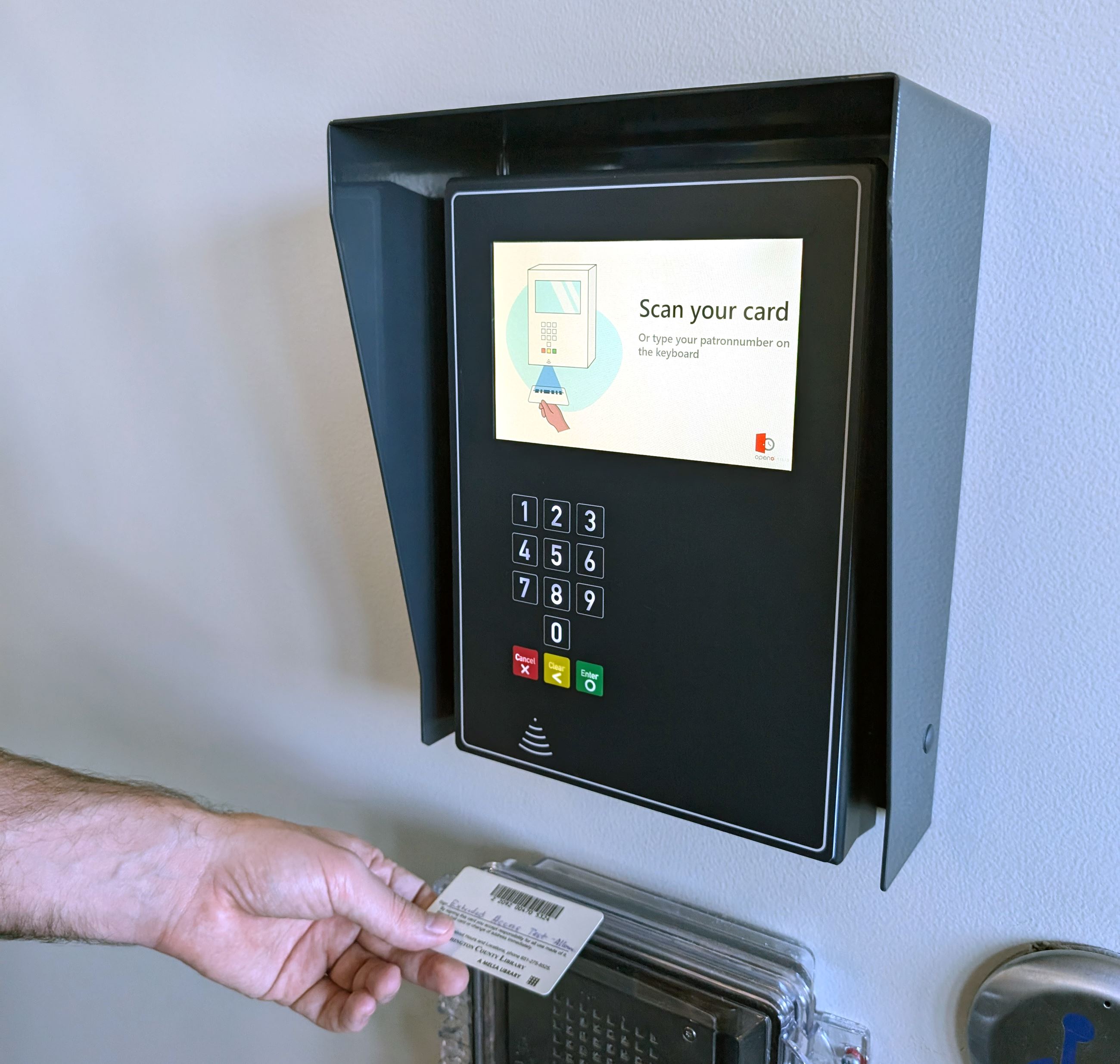 Hand holding a library card under the Extended Access card reader at Valley Library.